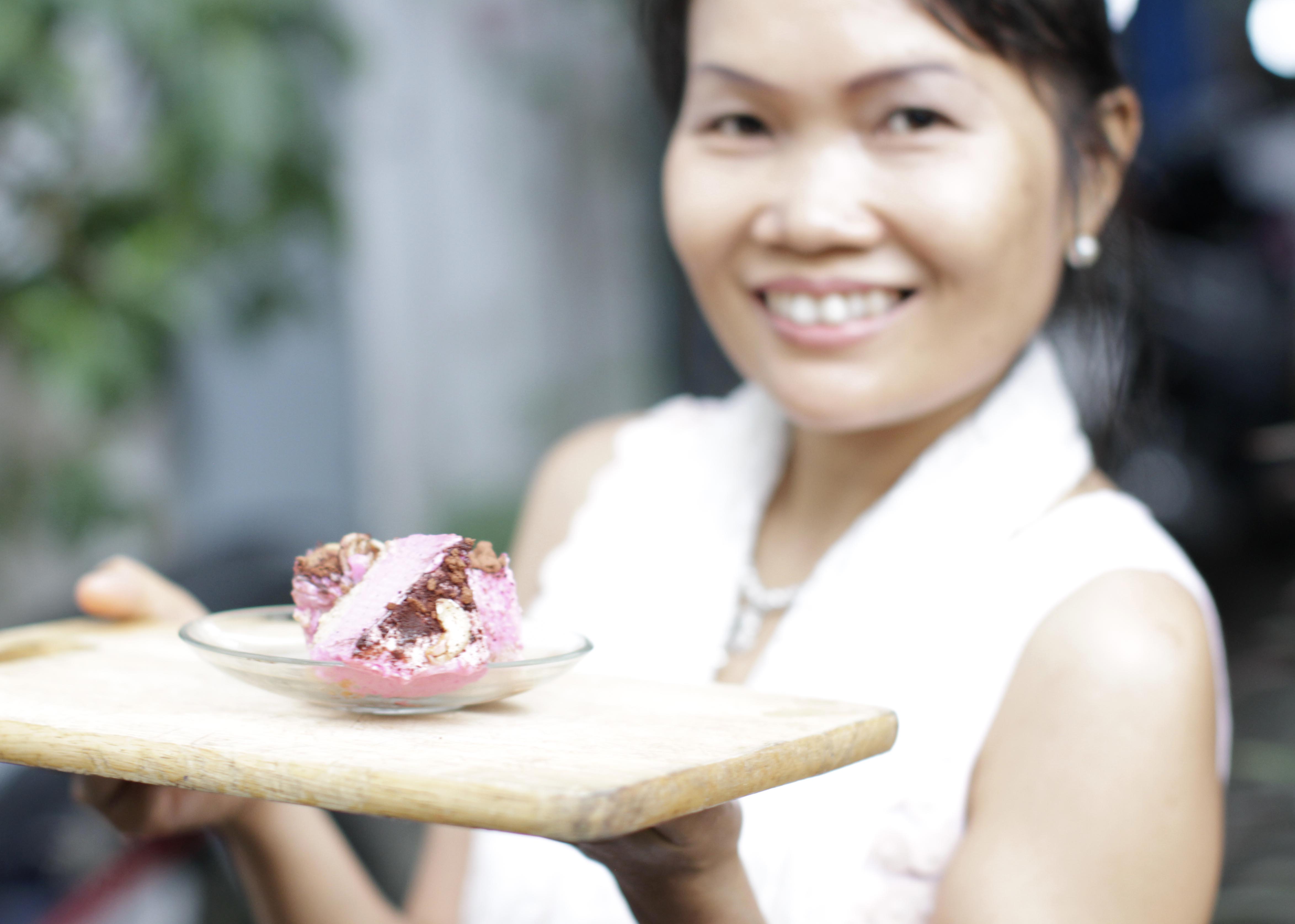 Our founder May holiding a plate of vegan magenta dragonfruit ice cream cake.