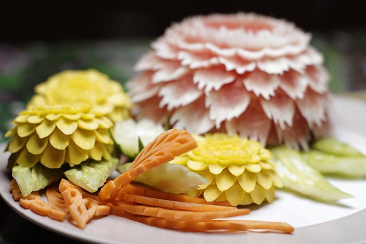 Finished fruit carving design consisting of watermelon and pumpkin flowers, and carrot leaves.