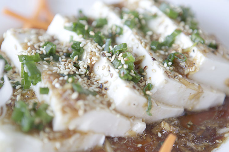Slices of freshly made tofu with chives and sauce.