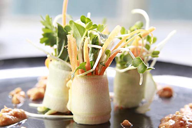 Raw vegan circular ice cream cake with strawberries. Two brown textured cake slices with white ice cream inside.