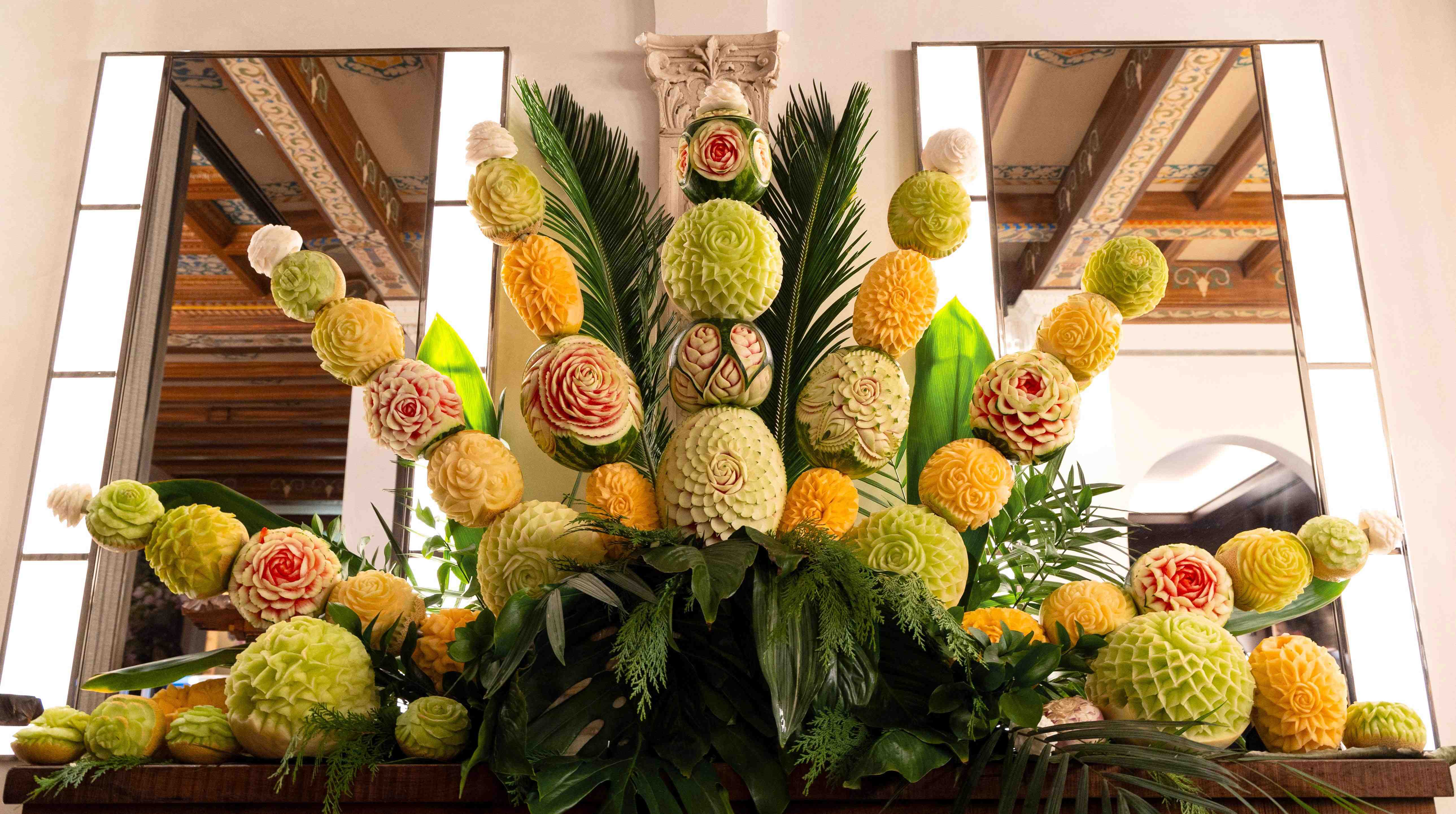 Massive fruit and vegetable carving sculpture with spires of carvings and leaves used for a table display for a culinary event