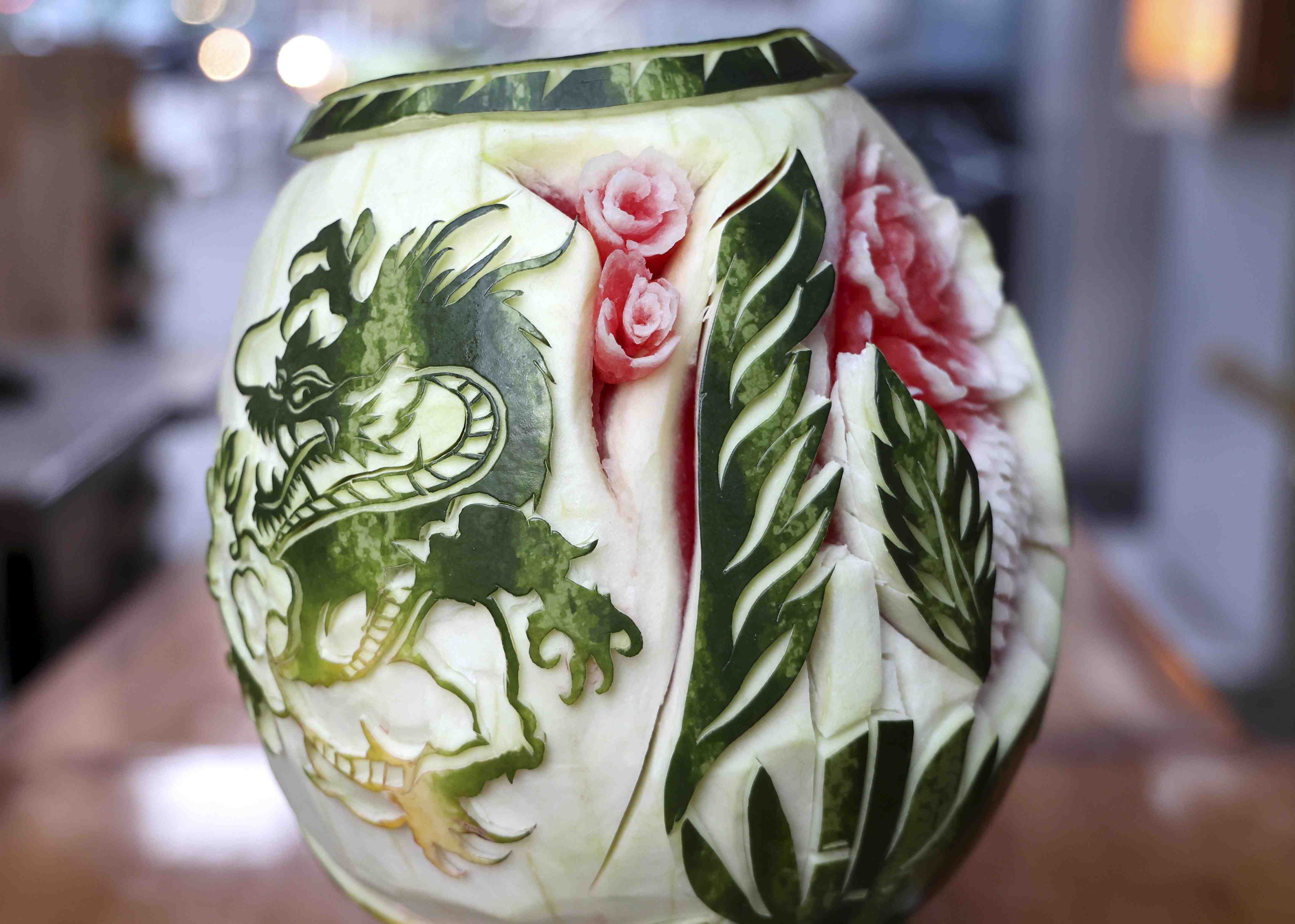 Watermelon carving with dragon motif, rose flowers and leaves carved into the surface of the fruit.